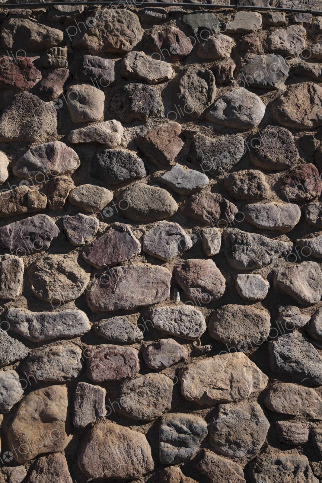 A stone wall with irregular shaped stone blocks fitted together.