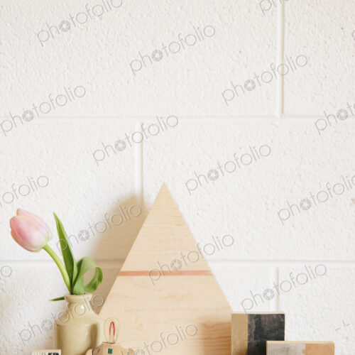 A stone worktop with a wooden triangle of wood, small cubes of wood and a pink tulip…