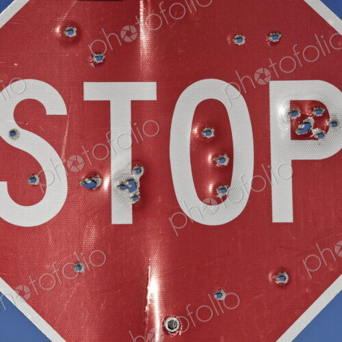A stop sign that has been shot multiple times with a high powered rifle. A stop sign that has been shot multiple times with a high powered rifle.