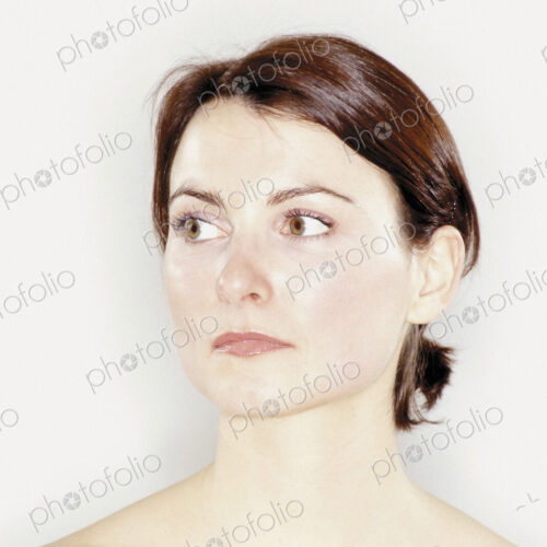 A studio portrait of a woman with brown hair tied back off her face. A studio portrait of a woman with brown hair tied back off her face.