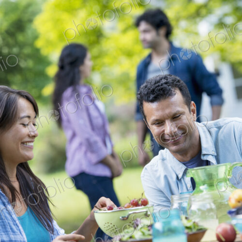 A summer party outdoors. A couple seated at a table.