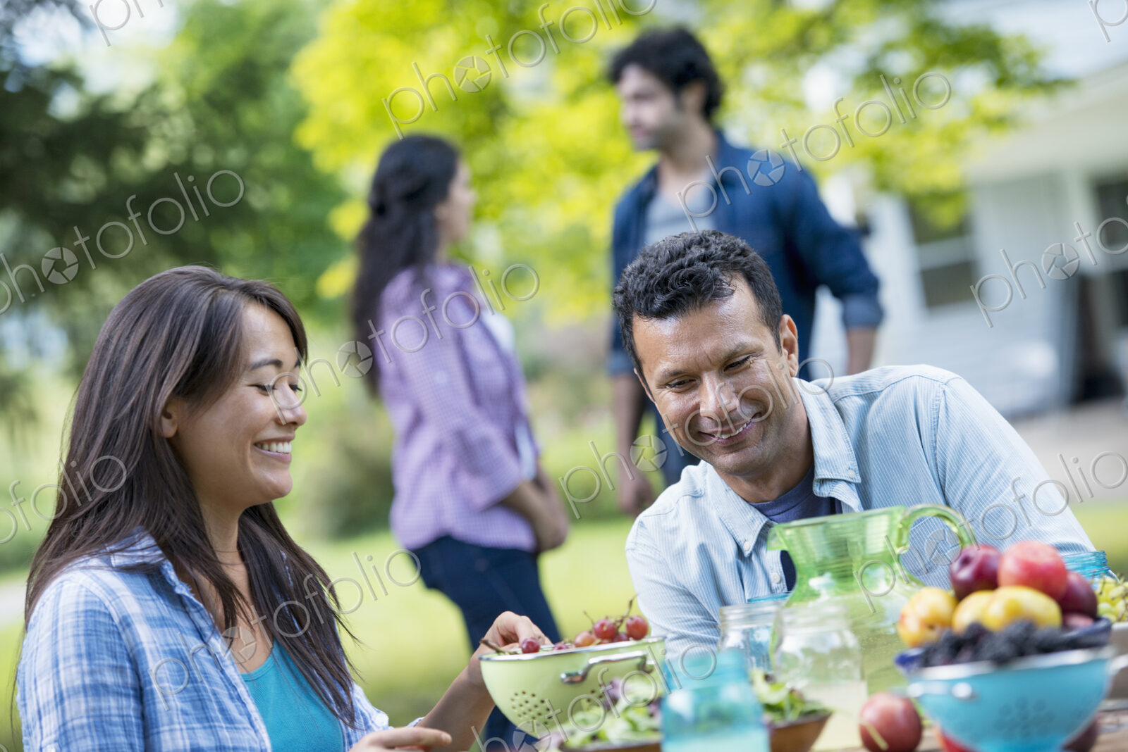 A summer party outdoors. A couple seated at a table.
