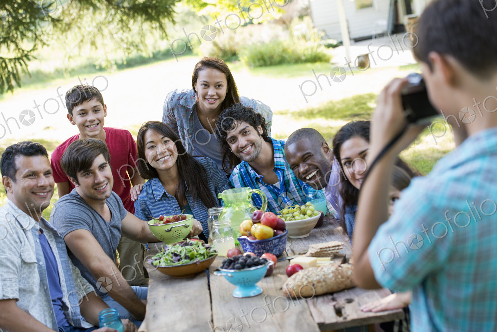 A summer party outdoors. Adults and children posing for a photograph.