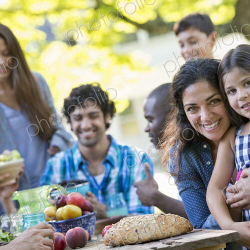 A summer party outdoors. Adults and children smiling and looking at the camera.