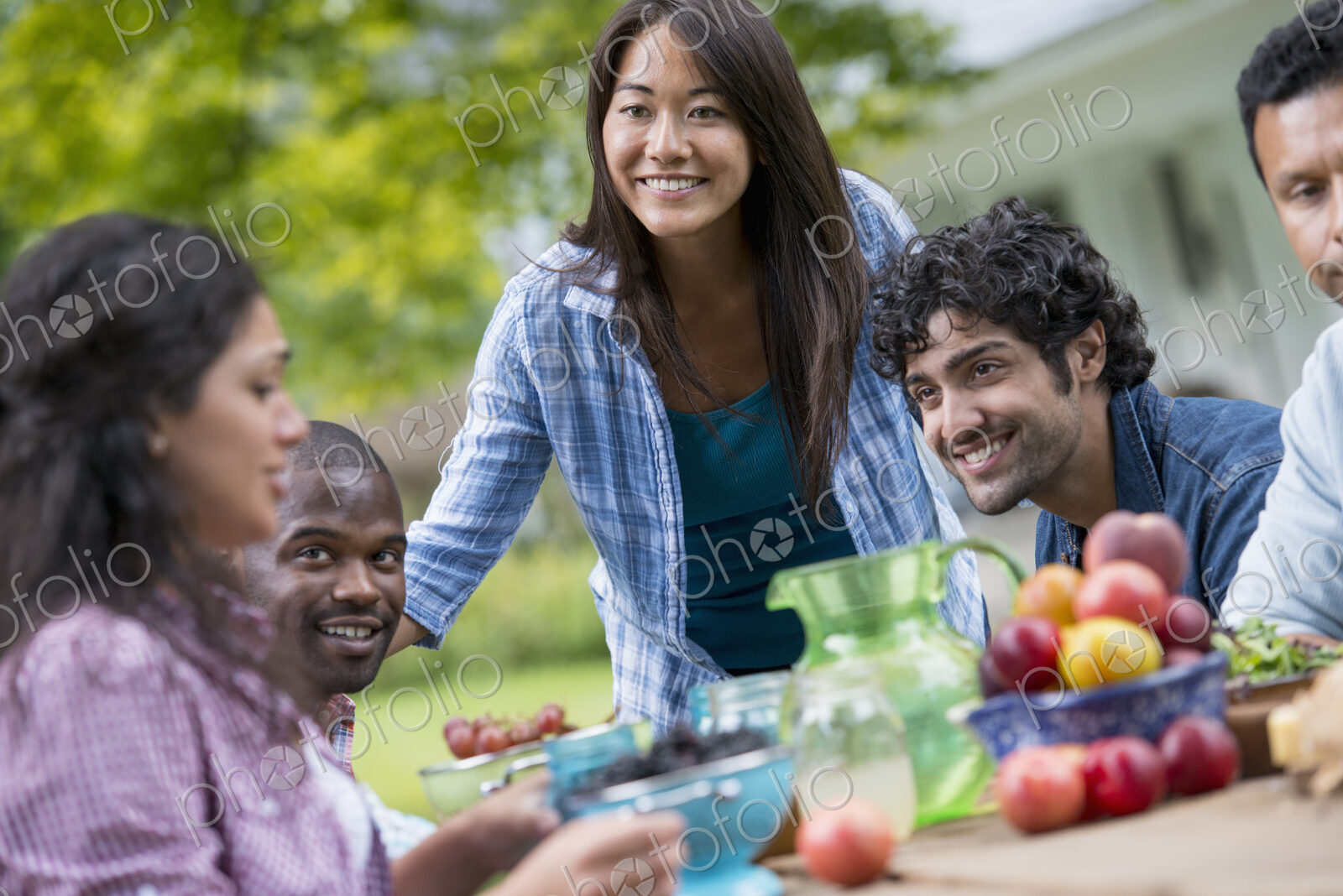 A summer party outdoors. Four people at a table.