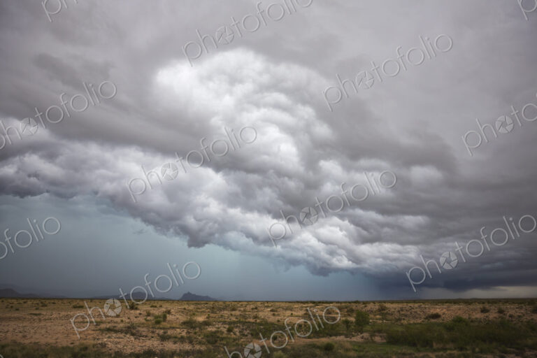 A supercell storm, cloud formations just above the horizon, white clouds and grey layers.