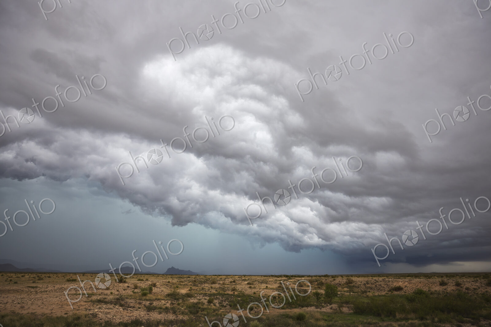 A supercell storm, cloud formations just above the horizon, white clouds and grey layers.