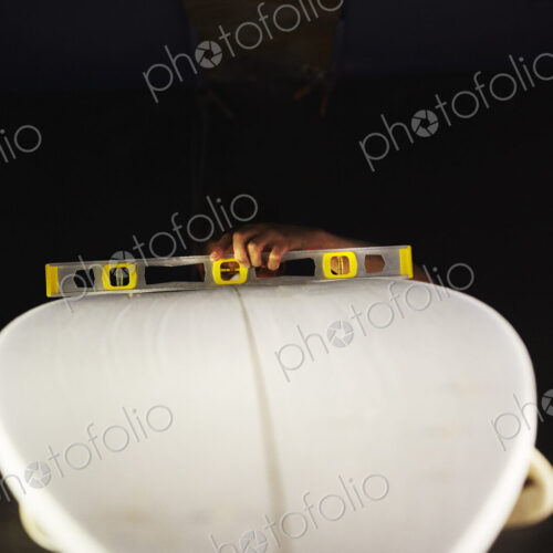 A surfboard in a workshop with a spirit level on the top.