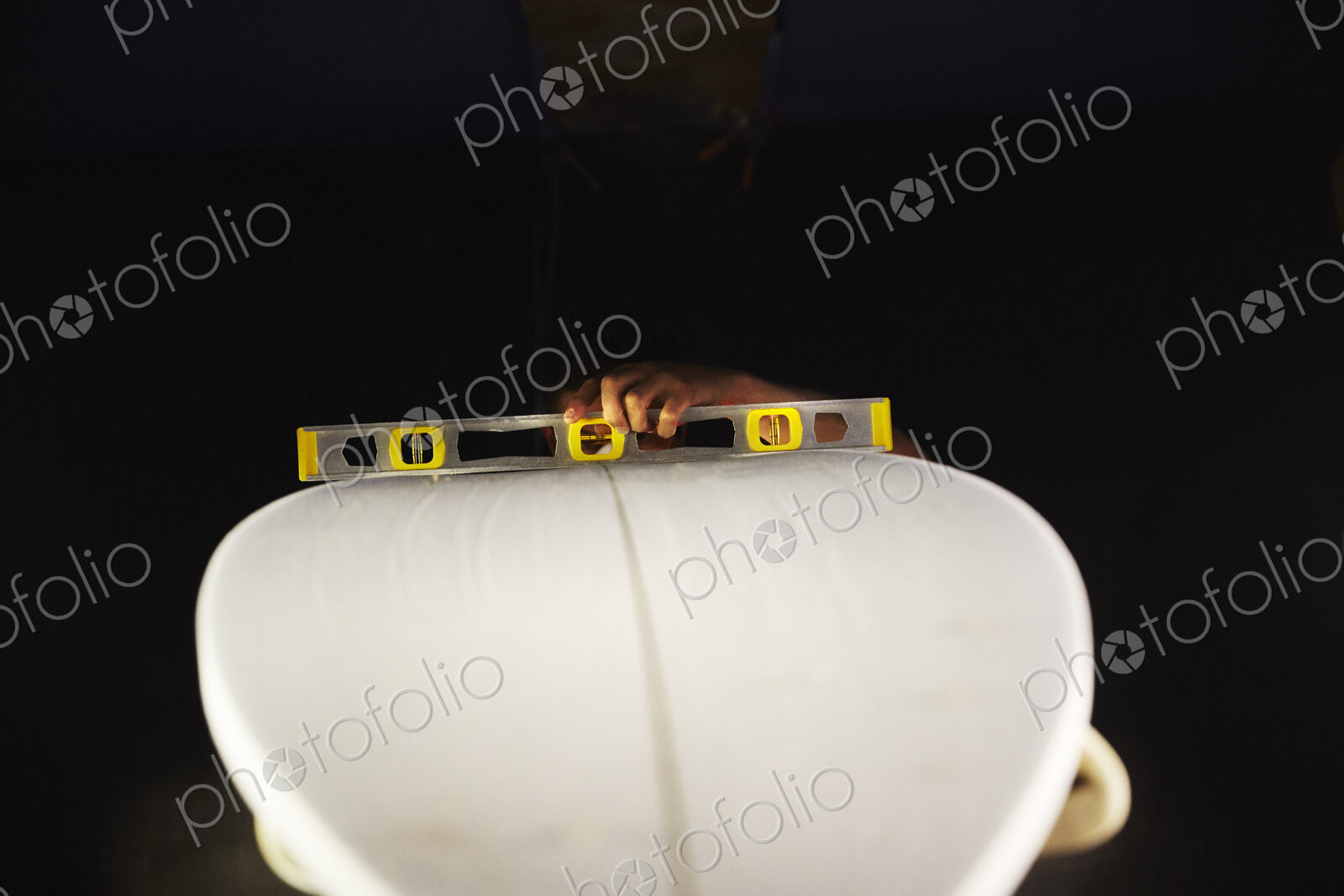 A surfboard in a workshop with a spirit level on the top.