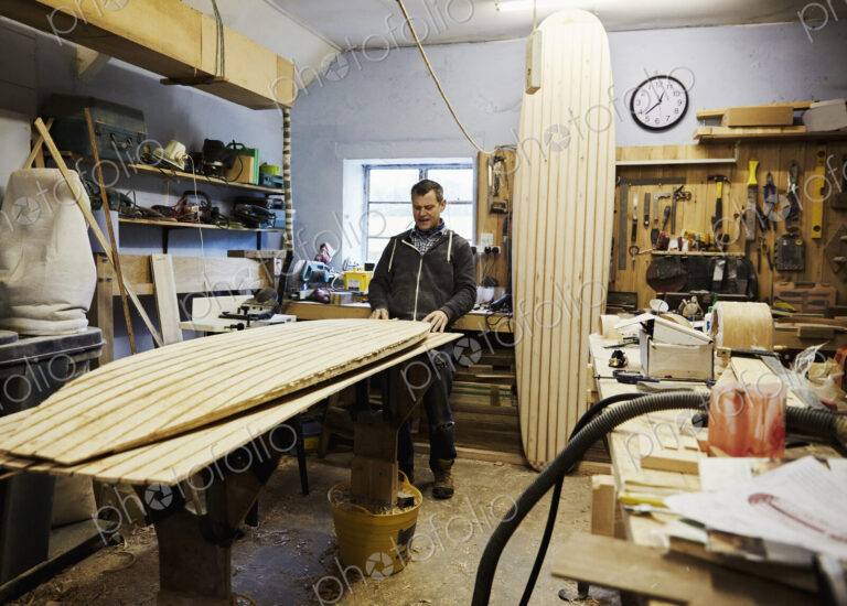 A surfboard workshop, a long board leant upright and a board in production on a…