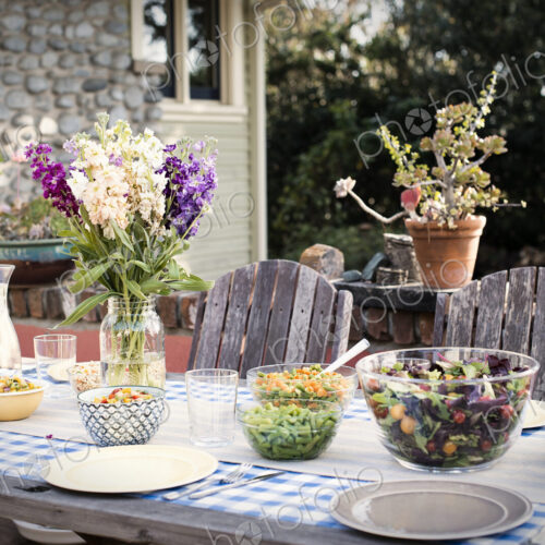 A table set for a meal outdoors in a garden. A table set for a meal outdoors in a garden.
