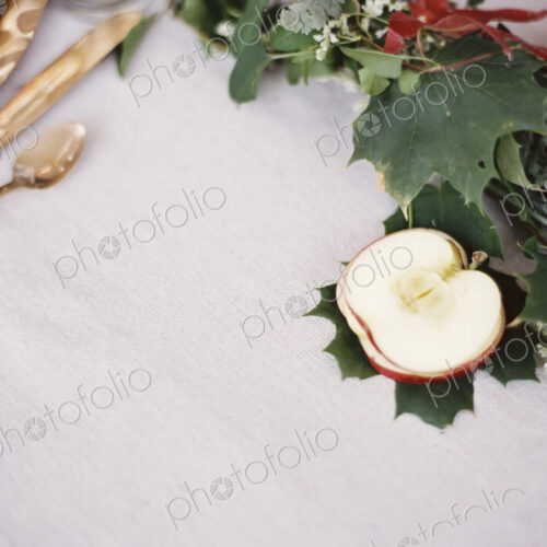 A table top covered with a white cloth. A place setting with cutlery and plate. An…