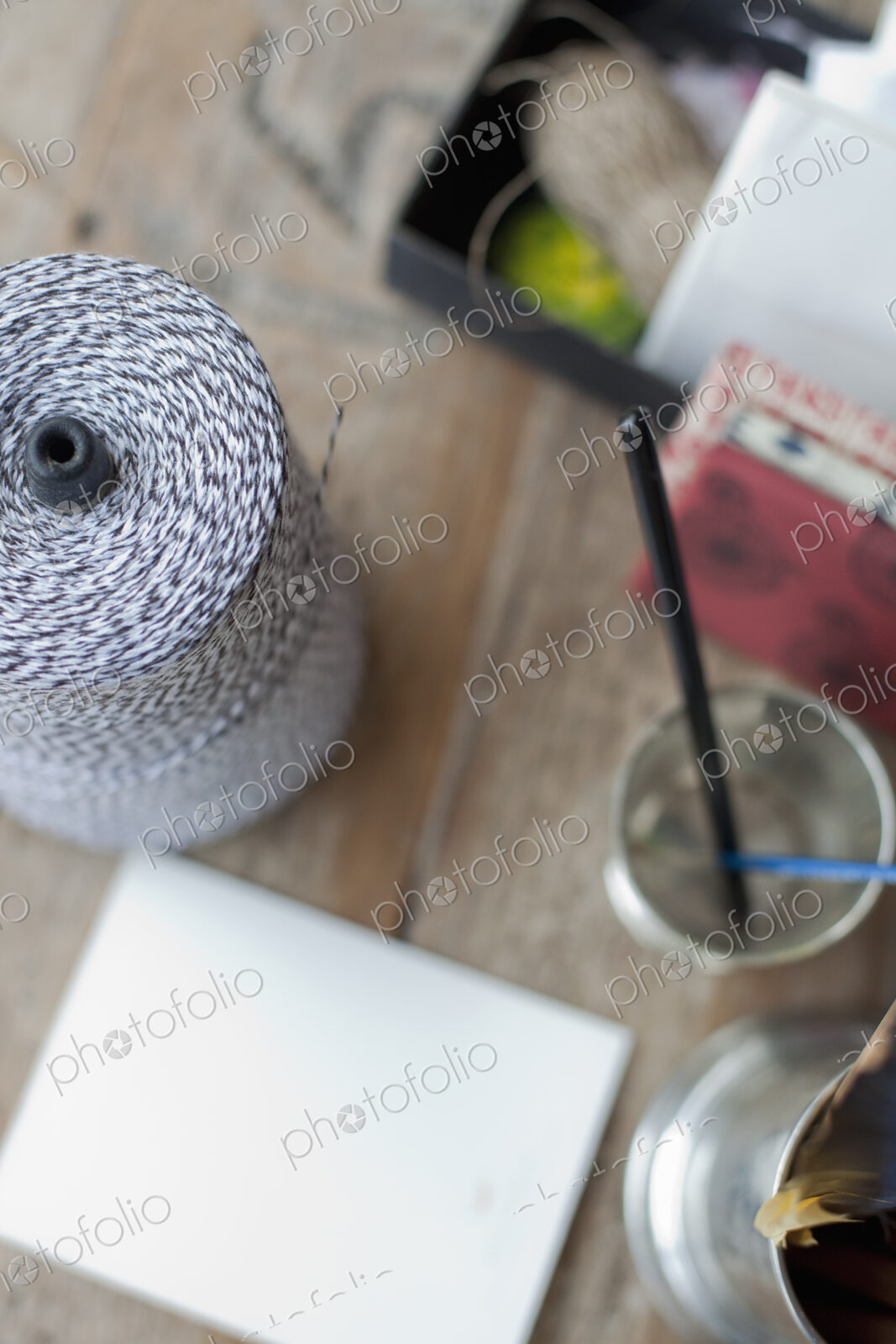 A table top with a small group of objects. Tankard and pencils, paper and a large ball…