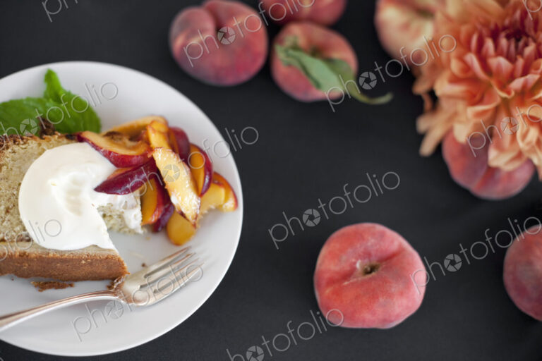 A table viewed from overhead. Organic fruit, peaches, and flowers. a plate with fresh…