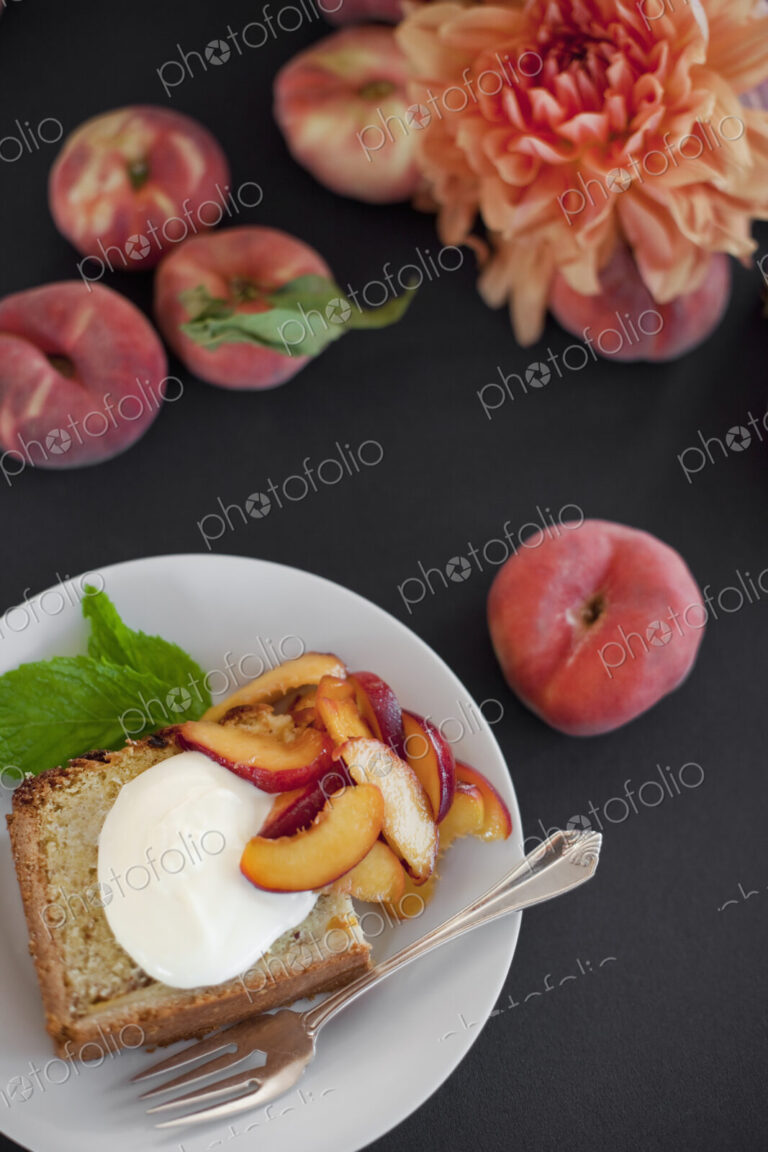 A table viewed from overhead. Organic fruit, peaches, and flowers. a plate with fresh…