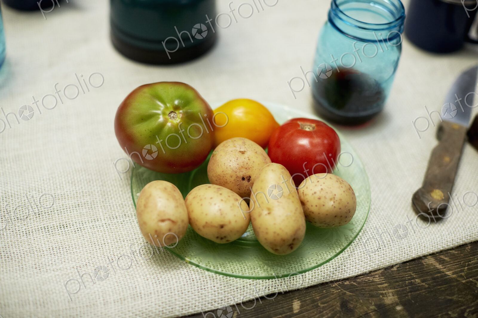 A table with a cloth, and plate with potatoes and tomatoes.