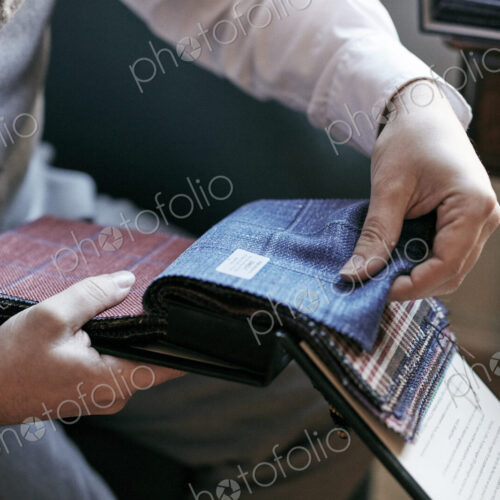 A tailor looking at fabric samples in a book, tweed and wool for mens clothes. A tailor looking at fabric samples in a book, tweed and wool for mens clothes.