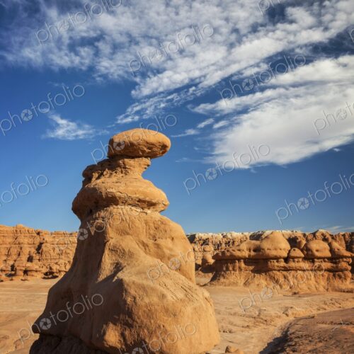 A tall hoodoo rock formation rises from the desert floor in Goblin Valley State Park,…