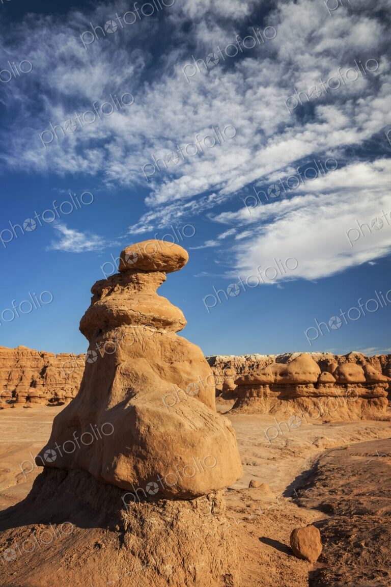 A tall hoodoo rock formation rises from the desert floor in Goblin Valley State Park,…