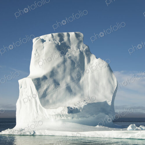 A tall iceberg on the waters of the shore of Greenland.