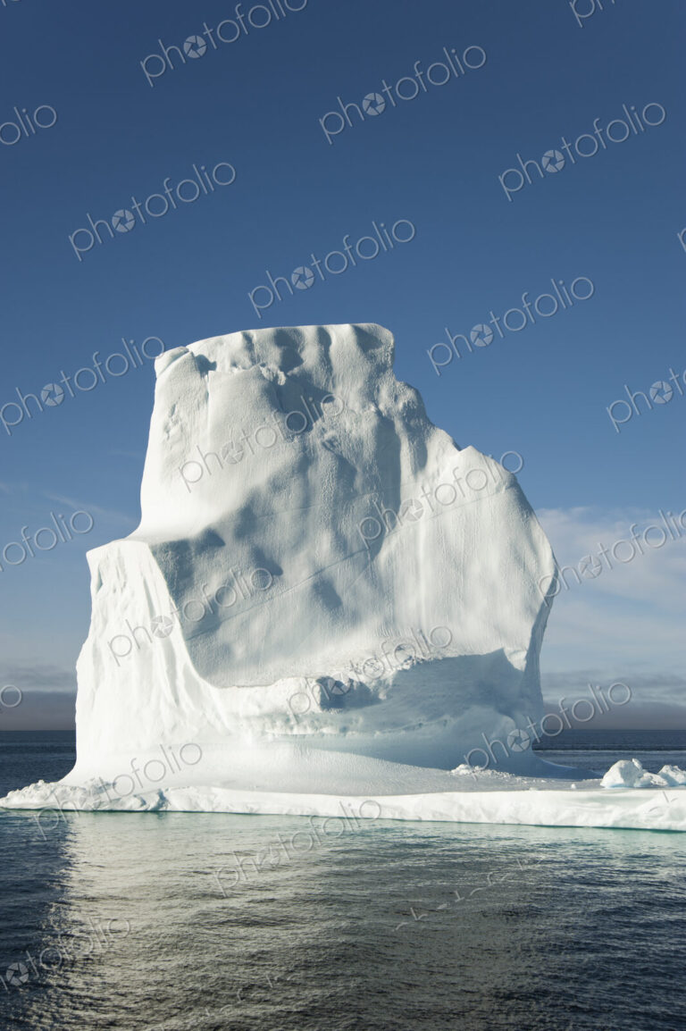 A tall iceberg on the waters of the shore of Greenland.