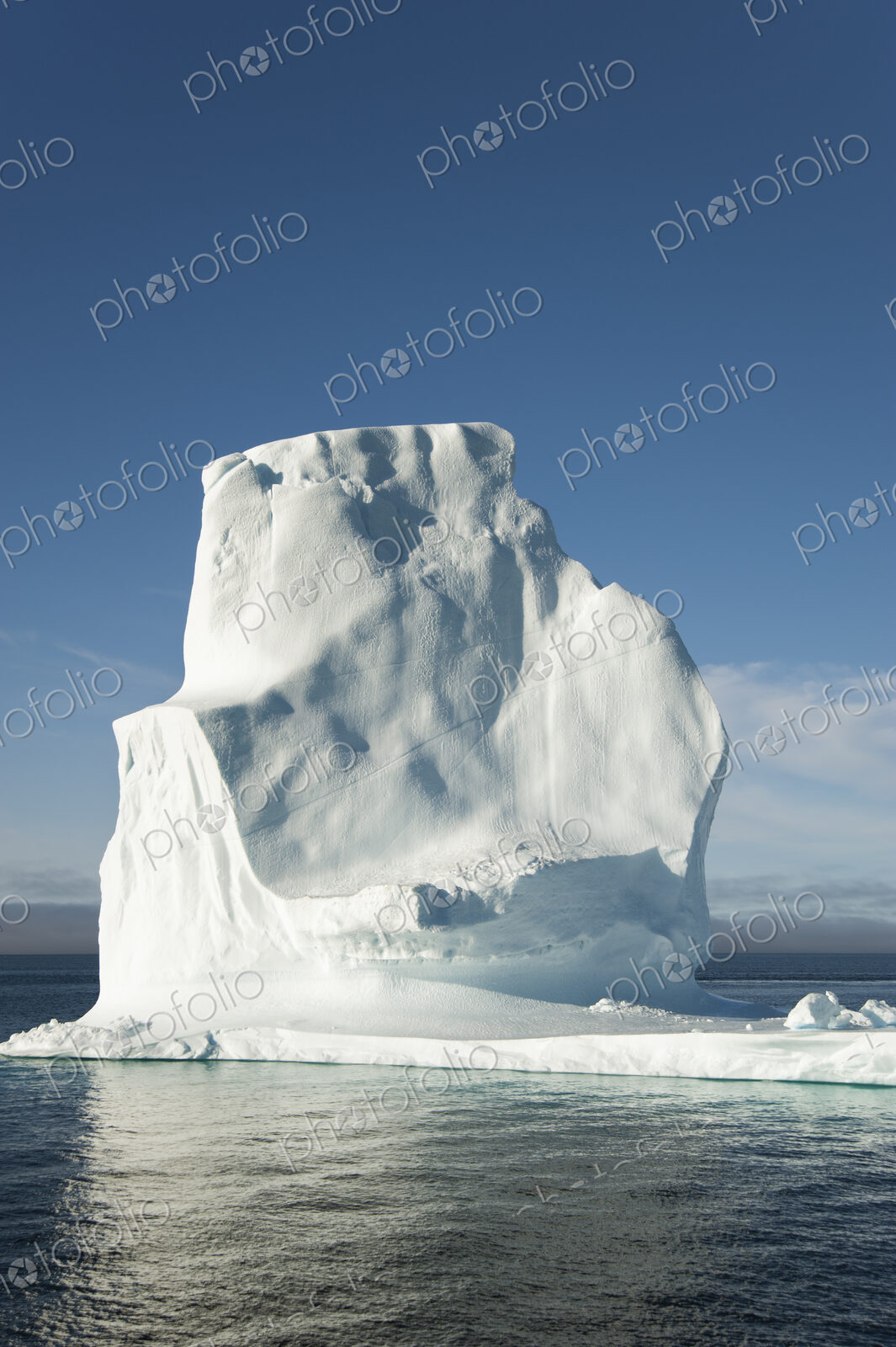 A tall iceberg on the waters of the shore of Greenland.