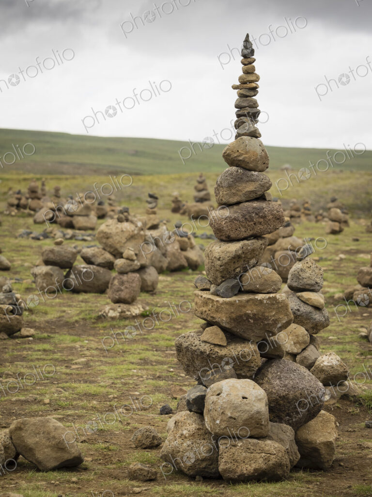 A tall rock cairn made by hikers to mark a spot on a walking path.