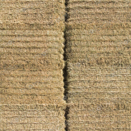 A tall stack of hay bales in a farmyard. Neatly packed and baled. A tall stack of hay bales in a farmyard. Neatly packed and baled.
