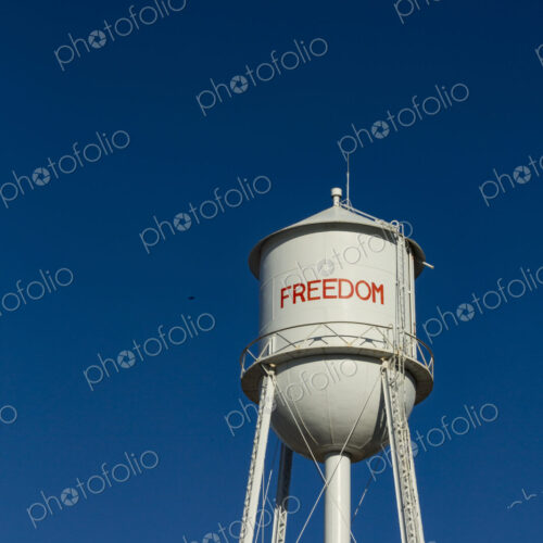 A tall water tower, view from below, painted with the name Freedom.