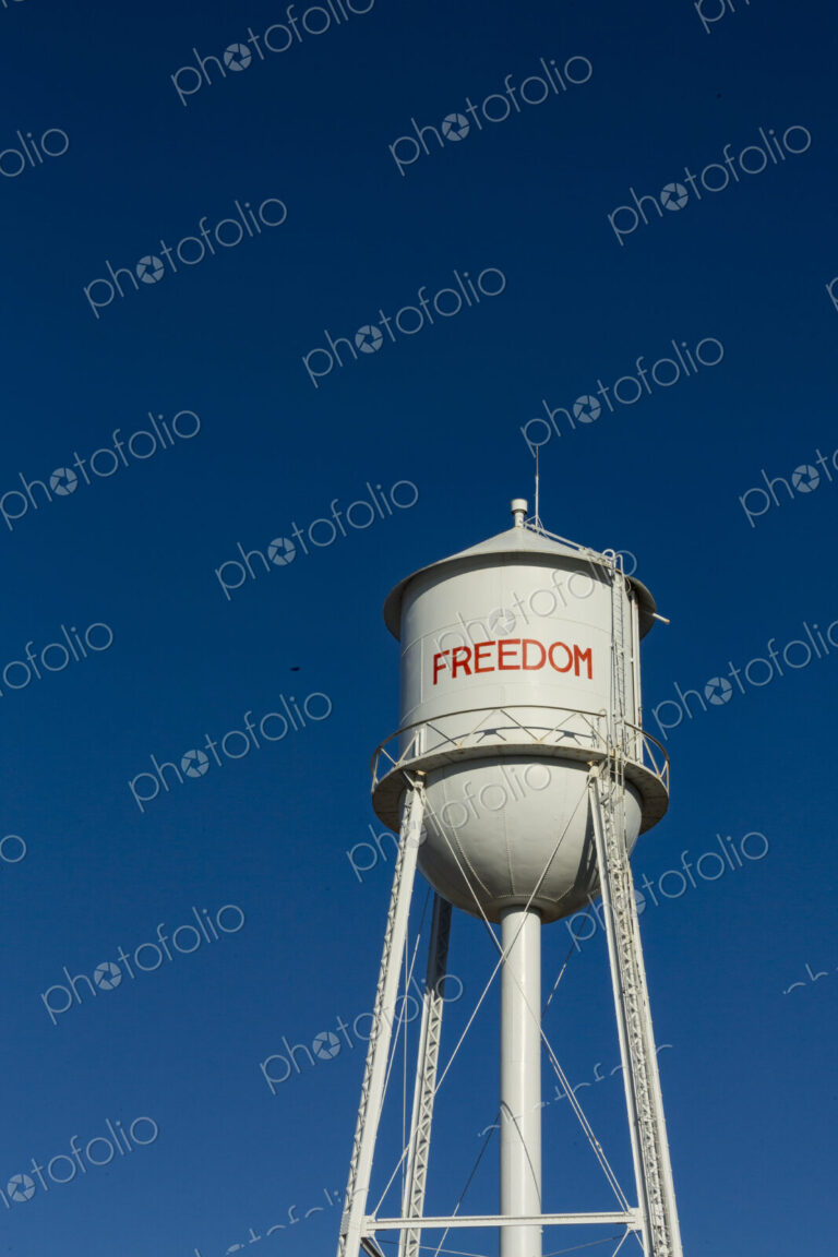 A tall water tower, view from below, painted with the name Freedom.