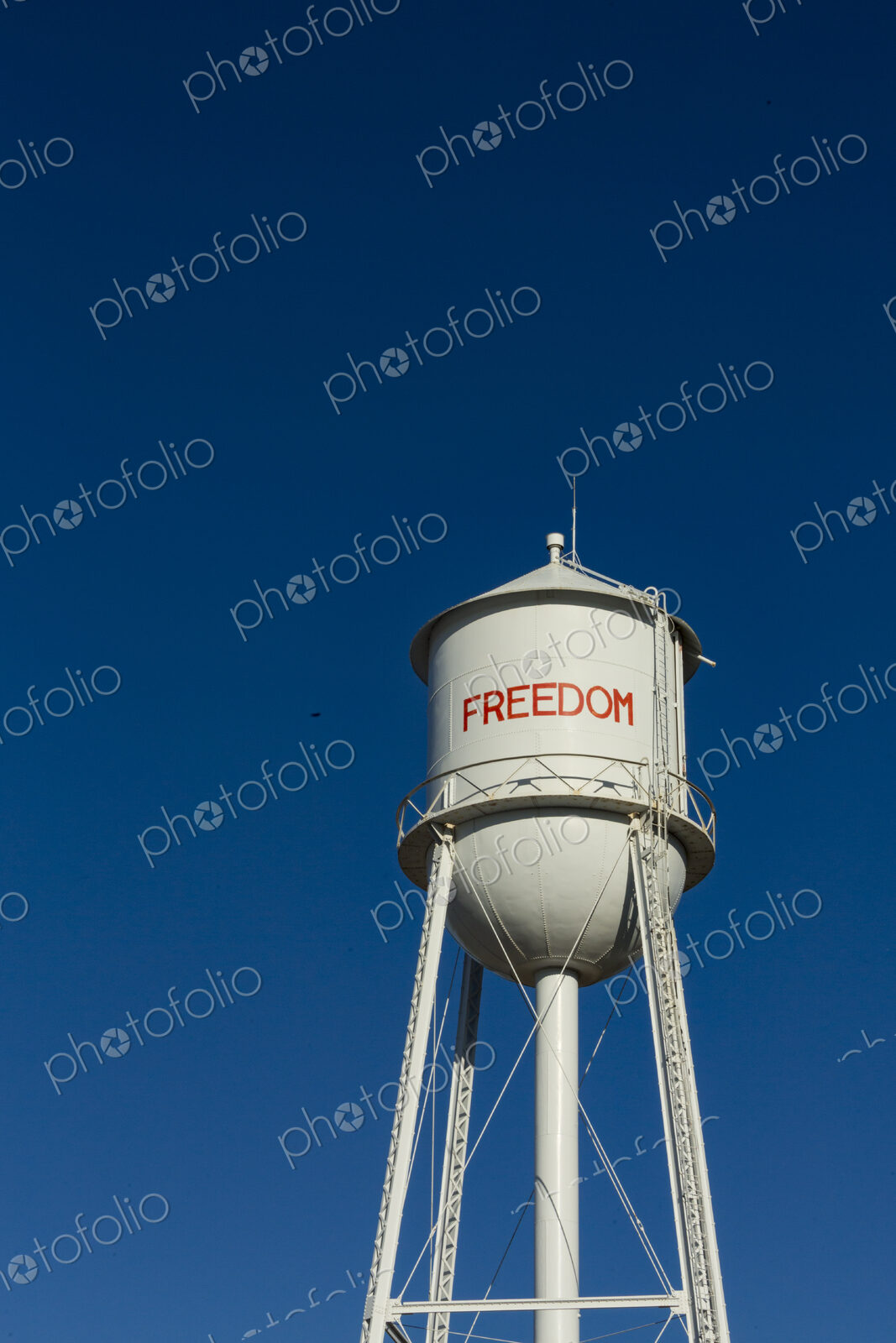 A tall water tower, view from below, painted with the name Freedom.