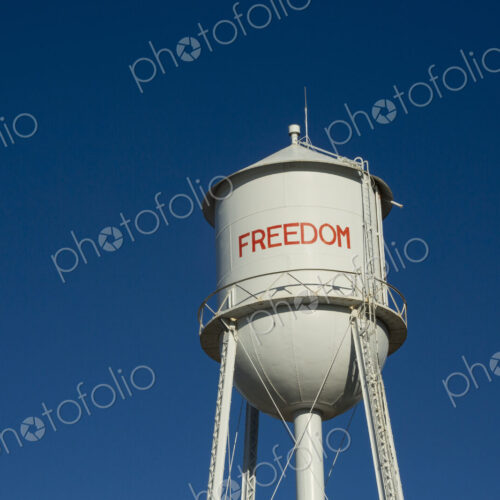 A tall water tower, view from below, painted with the name Freedom.