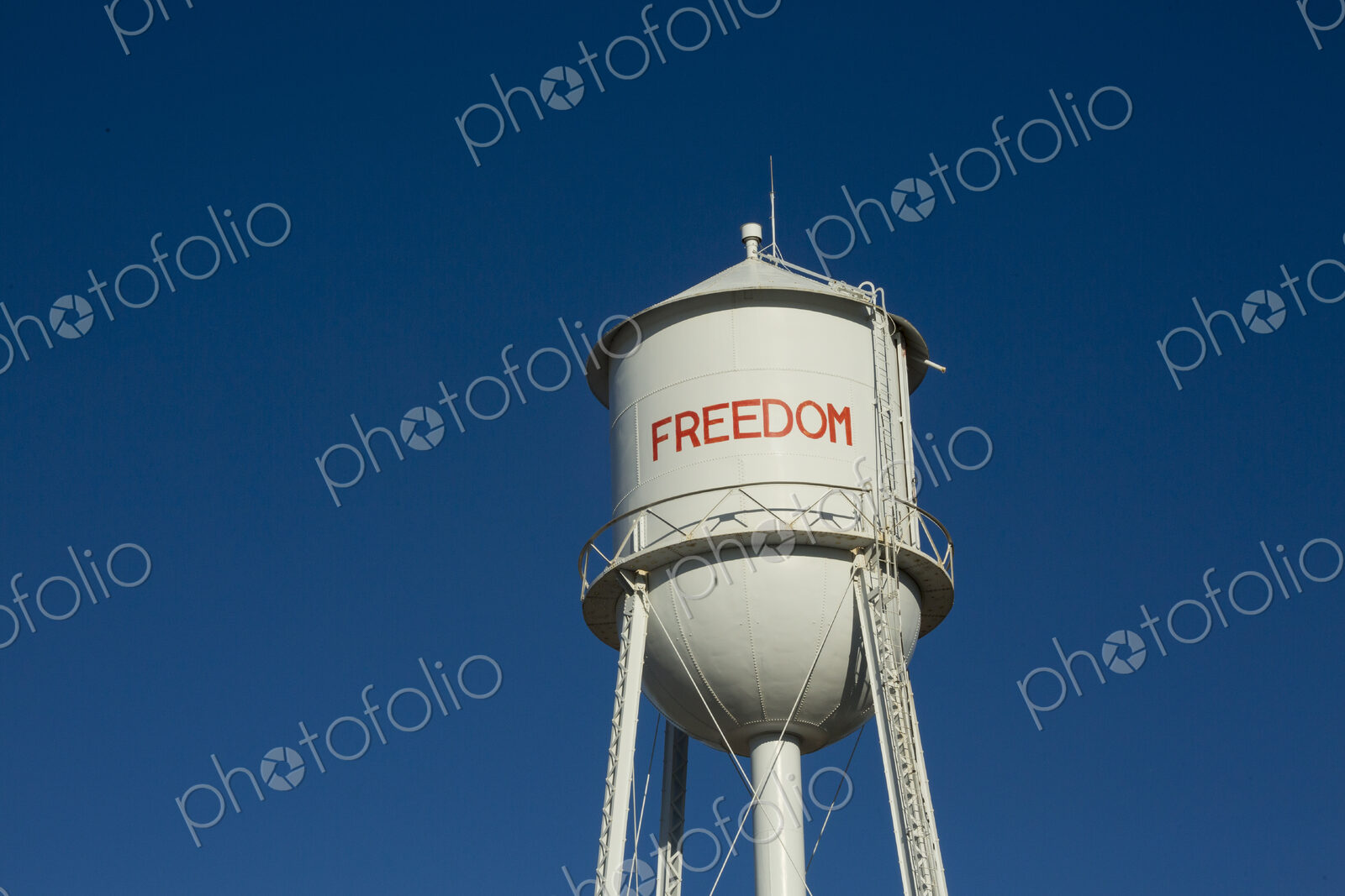 A tall water tower, view from below, painted with the name Freedom.