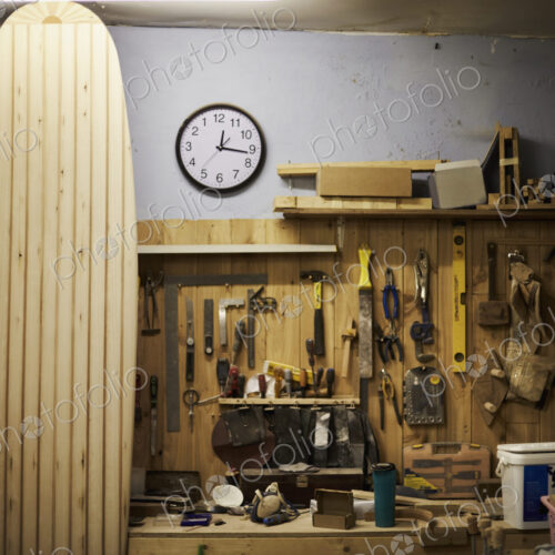 A tall wooden surfboard propped up in a workshop. A tall wooden surfboard propped up in a workshop.