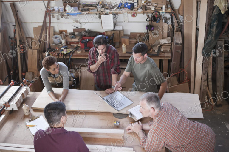 A team of multi-racial factory workers problem solving at a work station in a…