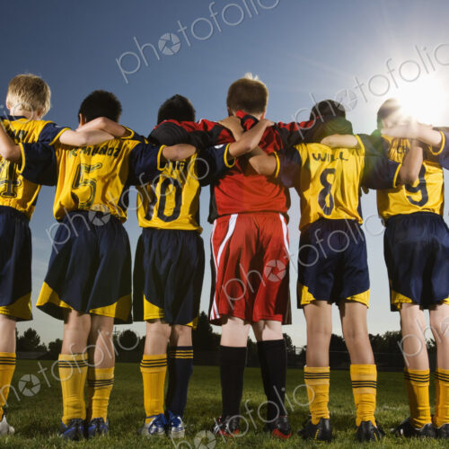 A team of soccer players standing in a row, arms around each other. A team of soccer players standing in a row, arms around each other.