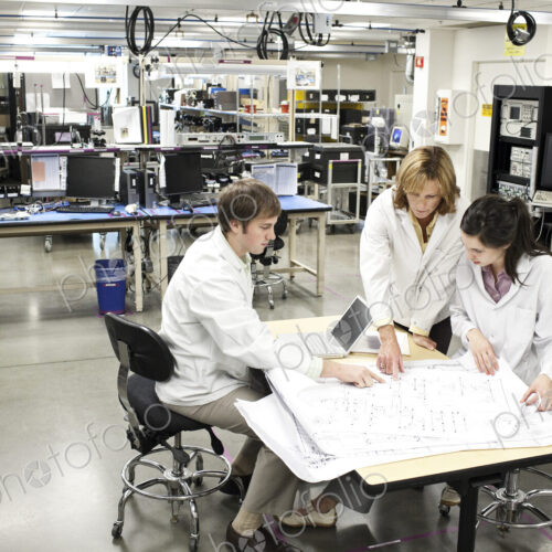 A team of technicians working over a problem in a technical research and development site. A team of technicians working over a problem in a technical research and development site.