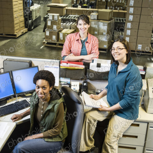 A team of three female warehouse workers at the front desk of a distribution warehouse. A team of three female warehouse workers at the front desk of a distribution warehouse.