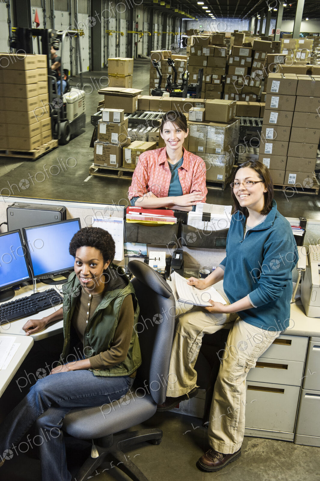 A team of three female warehouse workers at the front desk of a distribution warehouse.