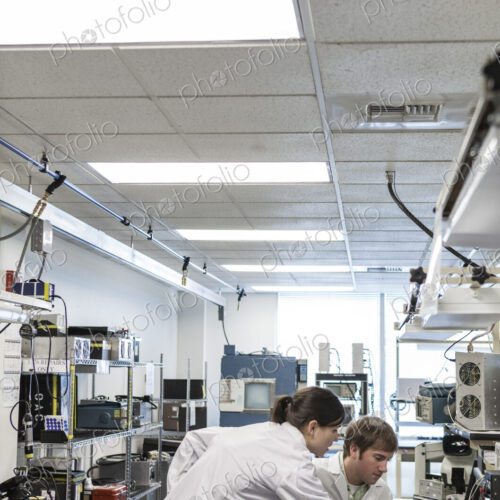 A team of two male and female technicians in white coats working together