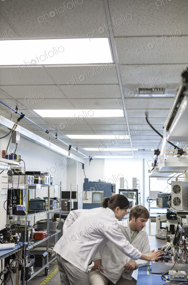 A team of two male and female technicians in white coats working together
