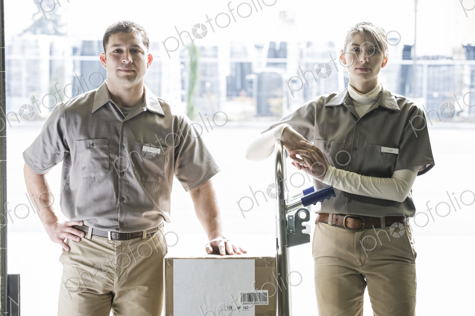 A team portrait of two caucasisn female and hispanic male uniformed warehouse workers .
