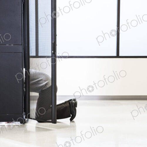 A technician working in the rack area of a computer server farm. A technician working in the rack area of a computer server farm.