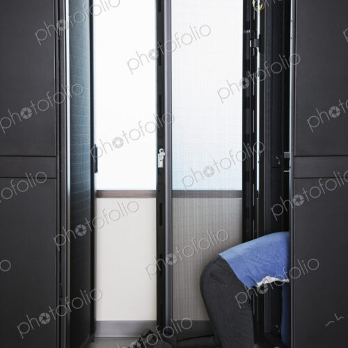 A technician working in the rack area of a computer server farm. A technician working in the rack area of a computer server farm.