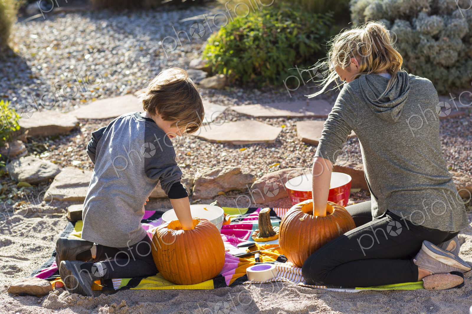 A teenage girl and her brother carving pumpkins at Halloween.