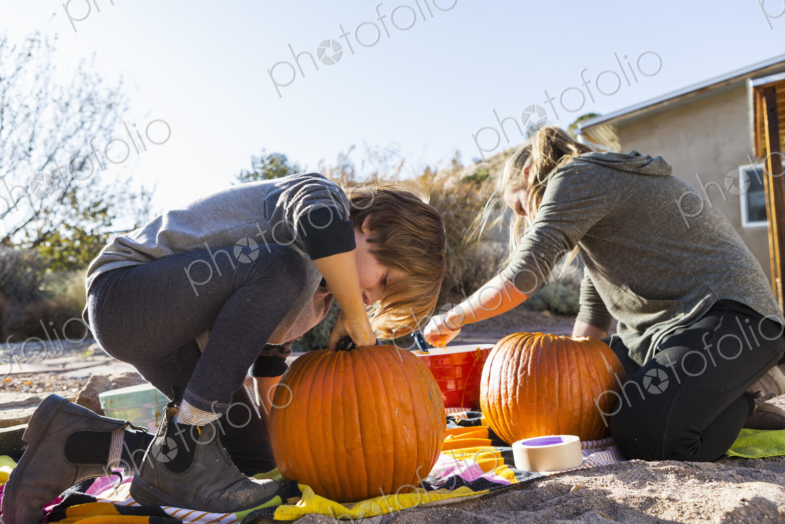 A teenage girl and her brother carving pumpkins at Halloween.