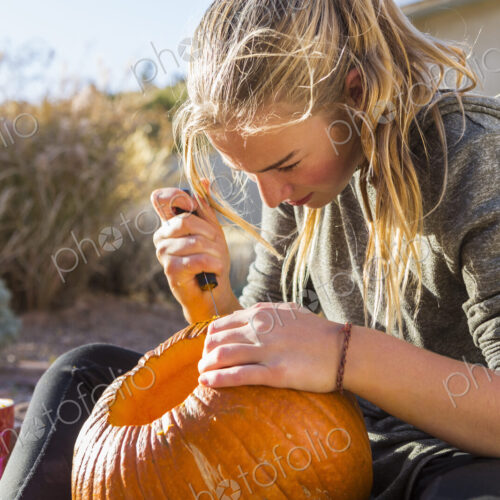 A teenage girl carving a pumpkin at Halloween, A teenage girl carving a pumpkin at Halloween,