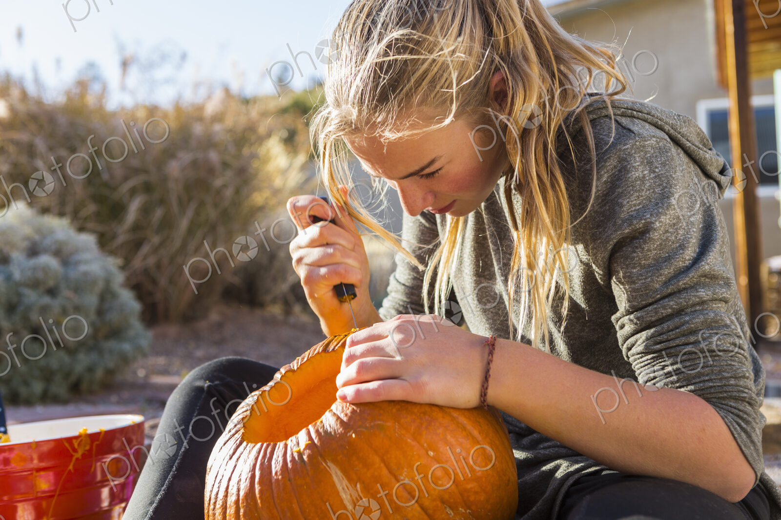 A teenage girl carving a pumpkin at Halloween,