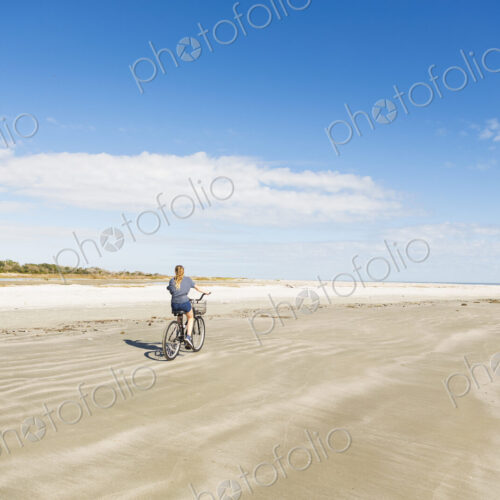 A teenage girl cycling on a beach