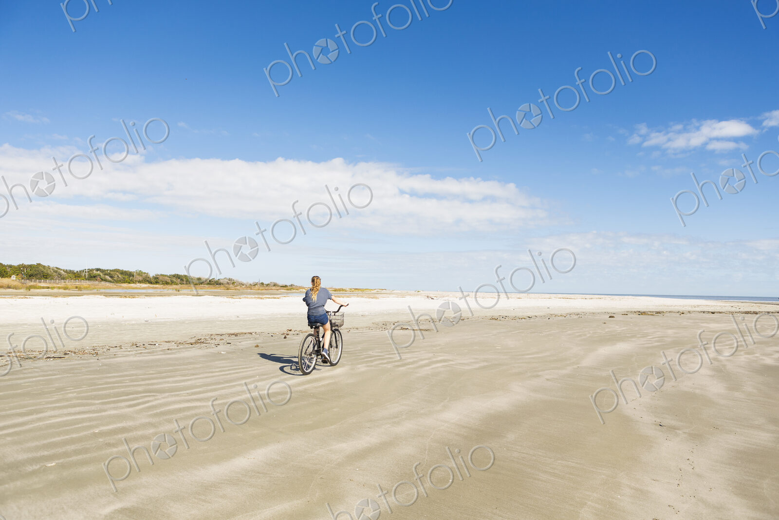 A teenage girl cycling on a beach
